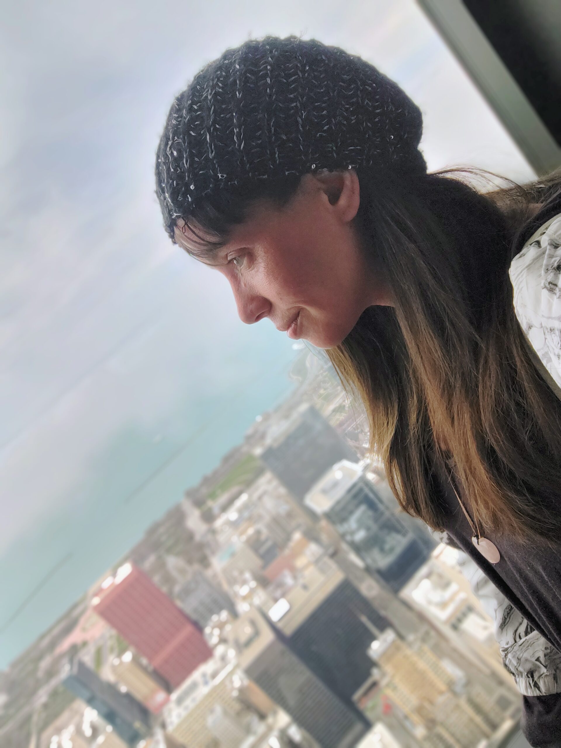 Nina looking thoughtfully through a high window over the city.
