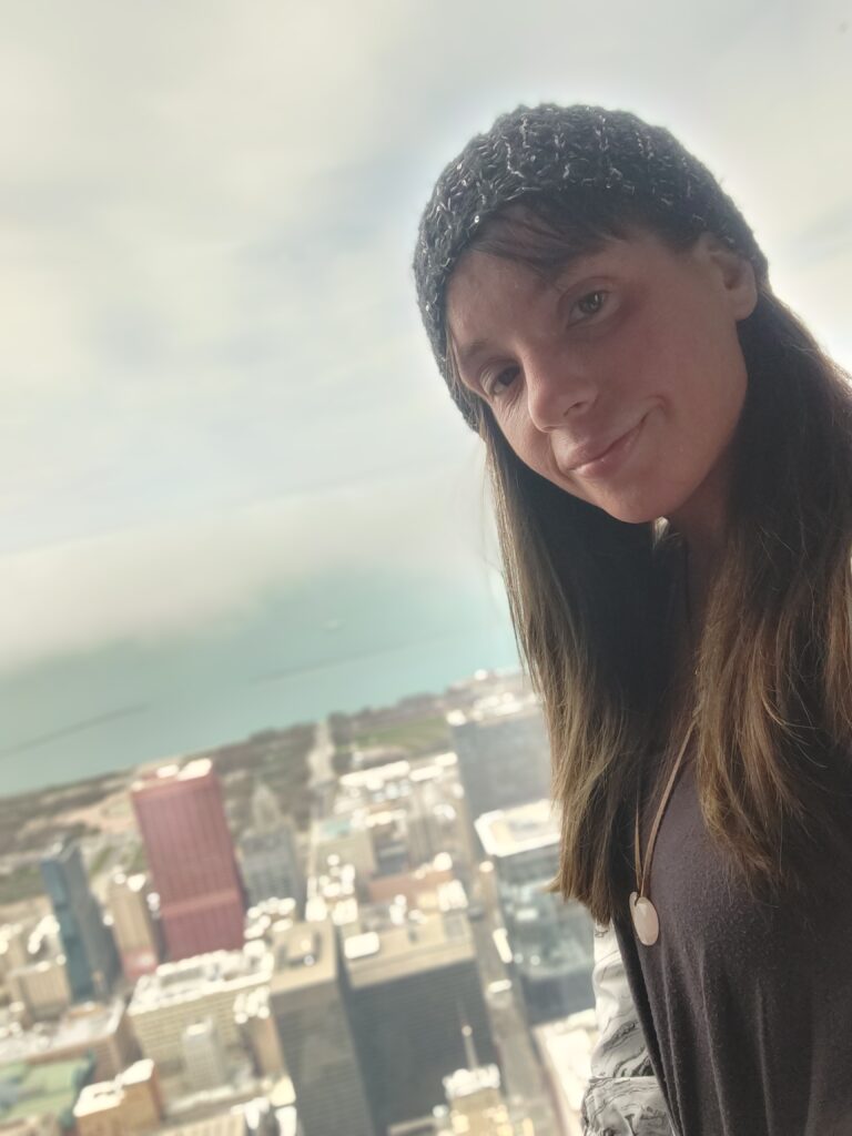 Portrait of Nina against a bright sky and distant city view.
