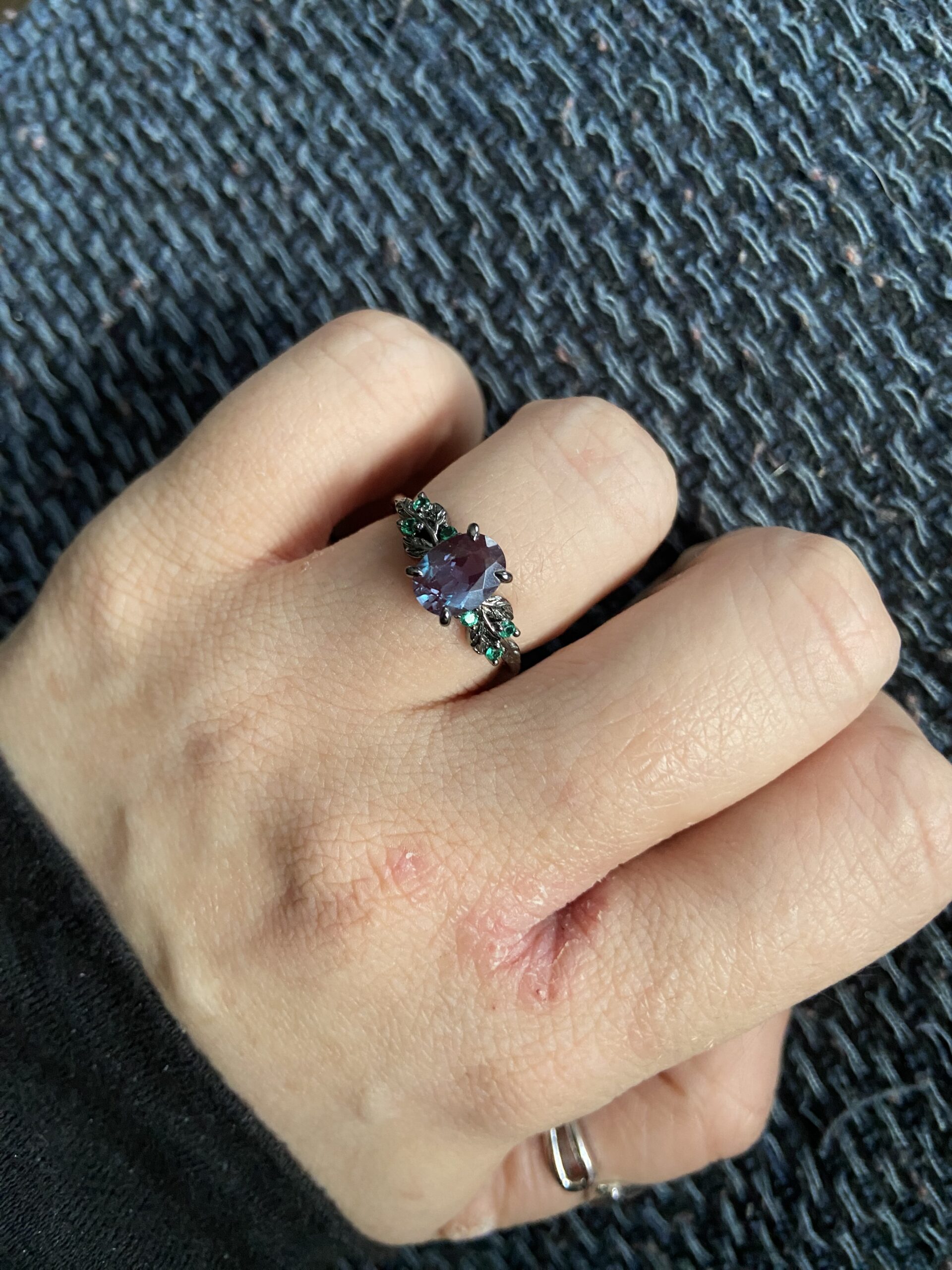 Nina’s hand wearing a purple gemstone ring, with natural skin texture visible.