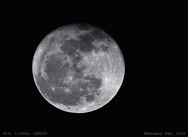 The moon glowing through a dark night sky.